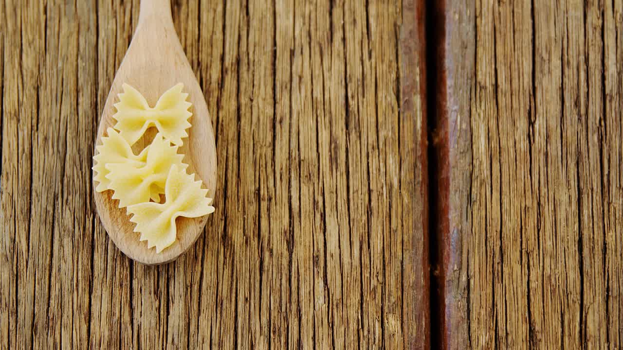 Bow tie pasta in spoon on wooden background