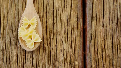 Bow-tie-pasta-in-spoon-on-wooden-background