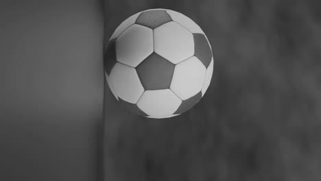 Vertical-pan-towards-black-white-classic-soccerball-in-hazy-smoke-black-background