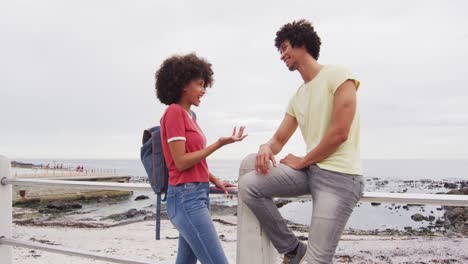 una joven pareja afroamericana hablando entre sí en el paseo cerca de la playa