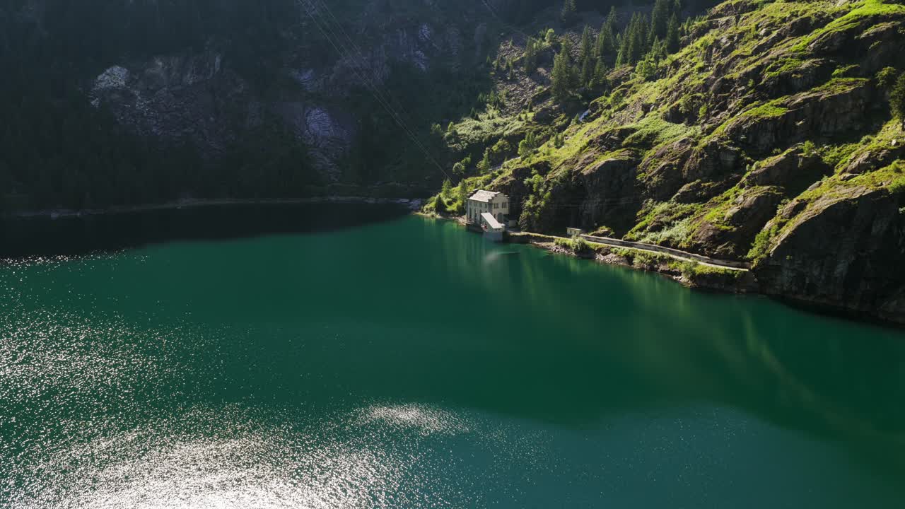 Antrona Lake with hydroelectric power plant on shore, scenic alpine landscape in Piedmont, Italy. Aerial drone ascending