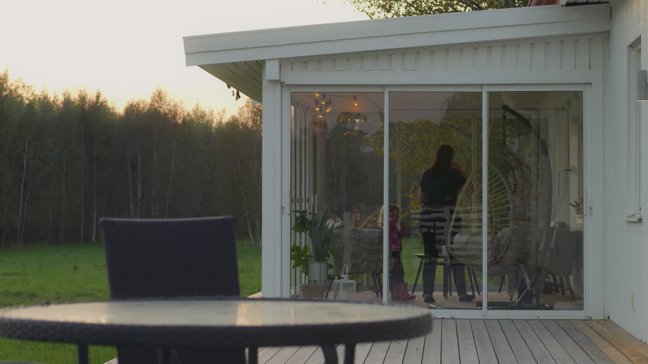 Family enjoying time together on a glass patio at sunset in the Finnish countryside