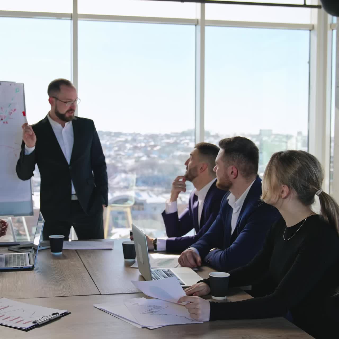 Business meeting in the office. Manager talks about the curve on the chart. Business people discuss the ideas in the big light office
