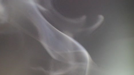 white smoke slowly floating through space against dark