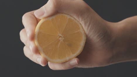 close-up of a hand squeezing a fresh lemon
