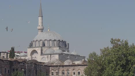 a majestic mosque with a large dome and tall minaret, set against a clear sky with birds flying overhead