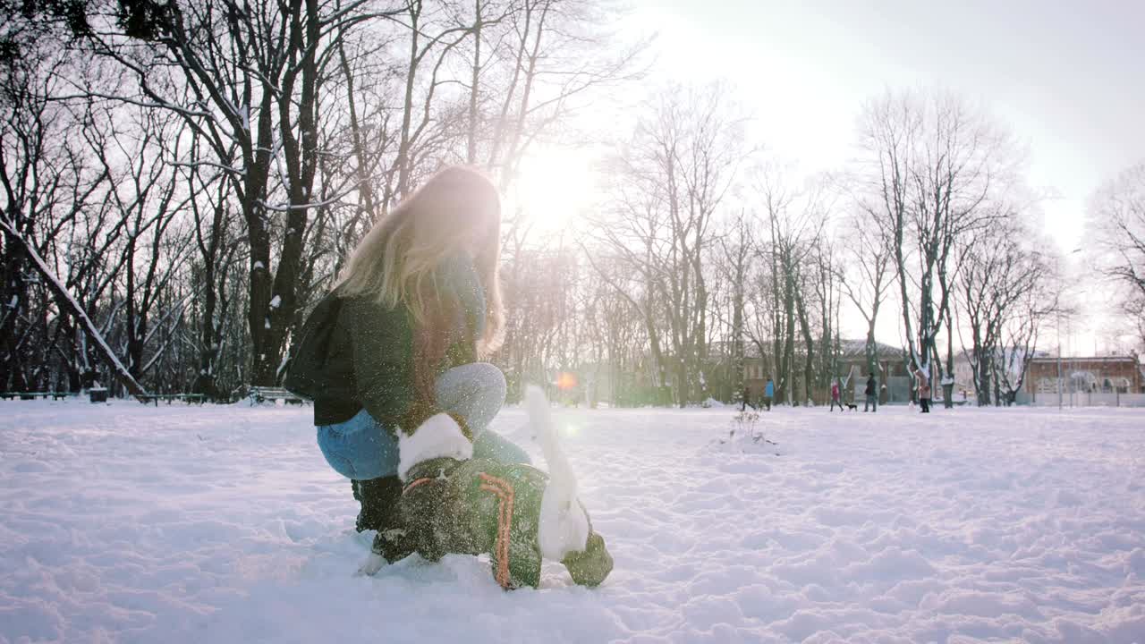 una mujer joven jugando con un jack russell terrier en invierno en la nieve, en cámara lenta.