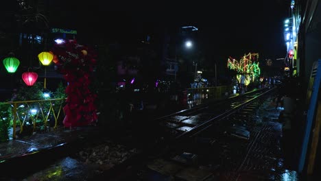 train moves through vibrant, lantern-lit street
