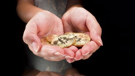 young-female-hands-holding-golden-bitcoins-in-isolated-black-background-macro-view-moving-backward-4k,-cryptocurrency-investment