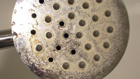 Dirty-shower-head-surface-with-residues-and-sediments,-handheld-closeup