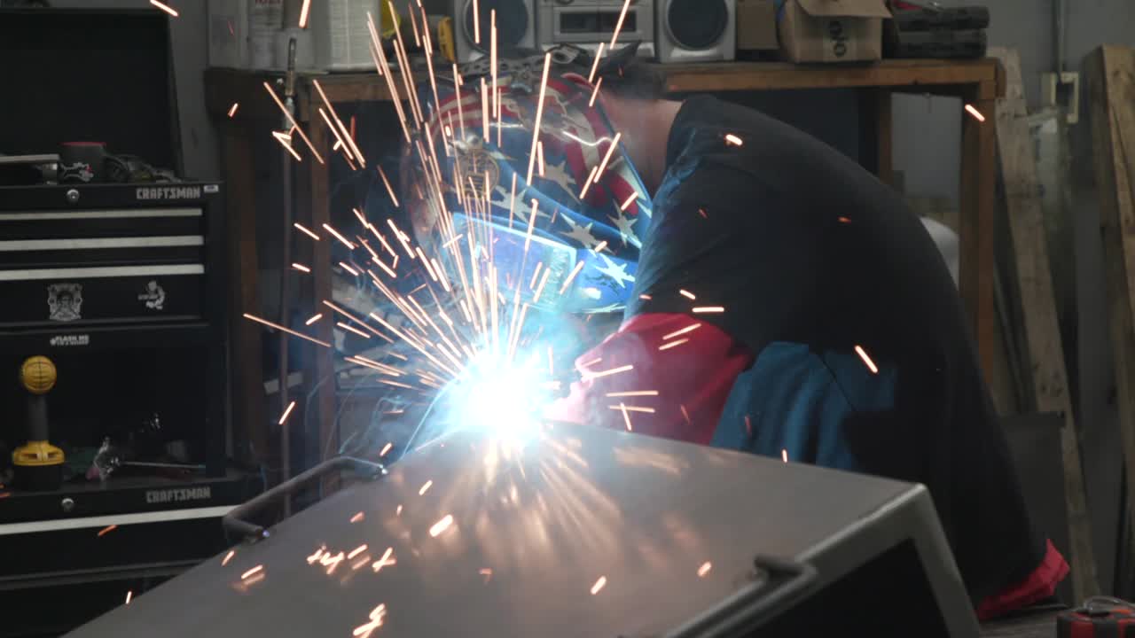 Man welding in an American Flag Helmet in a factory