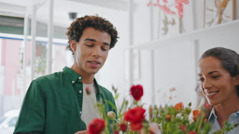 satisfied man smell flowers in shop. happy african guy buy bouquet in store.