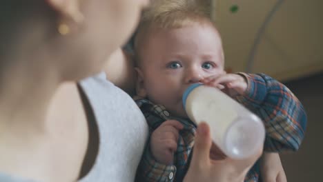 mama karmi zmęczone dziecko świeżym mlekiem w jasnym pokoju.