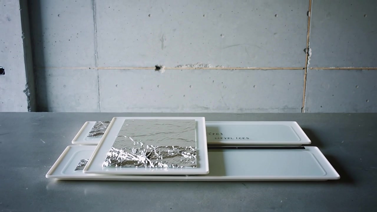 Sliding white trays with rail guiding top panel right on bench, revealing empty base and foil