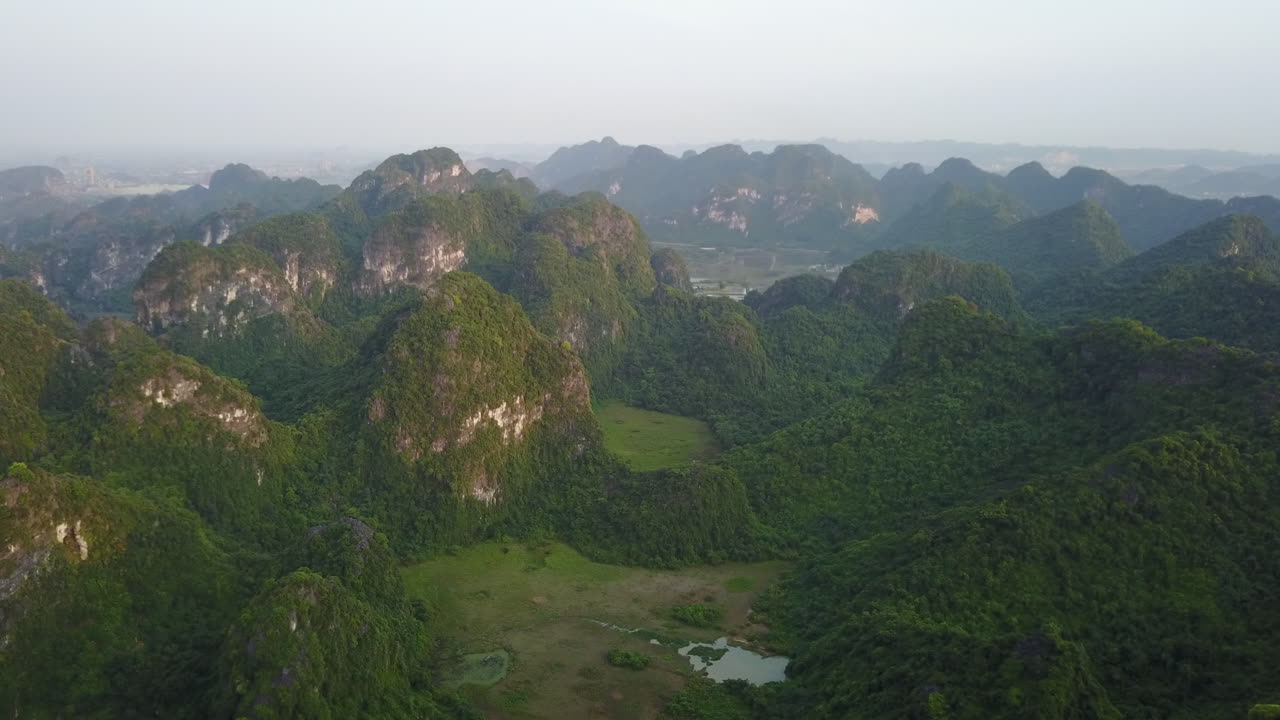 An amazing aerial view of the various karst rock formations in Ninh Binh, Vietnam, at sunrise. The soft morning light illuminates the stunning landscape of limestone peaks and lush valleys.