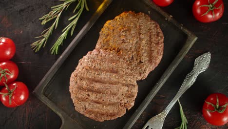 fried burger meat on a cutting board with tomatoes rotates.