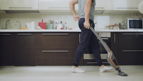 Happy-man-having-fun-with-vacuum-cleaner-at-kitchen.