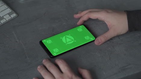 Holding-smartphone-with-horizontal-green-screen-chroma.-Mockup.