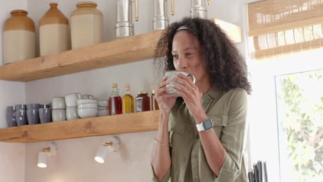 woman enjoying coffee in modern kitchen, smiling and relaxed, at home