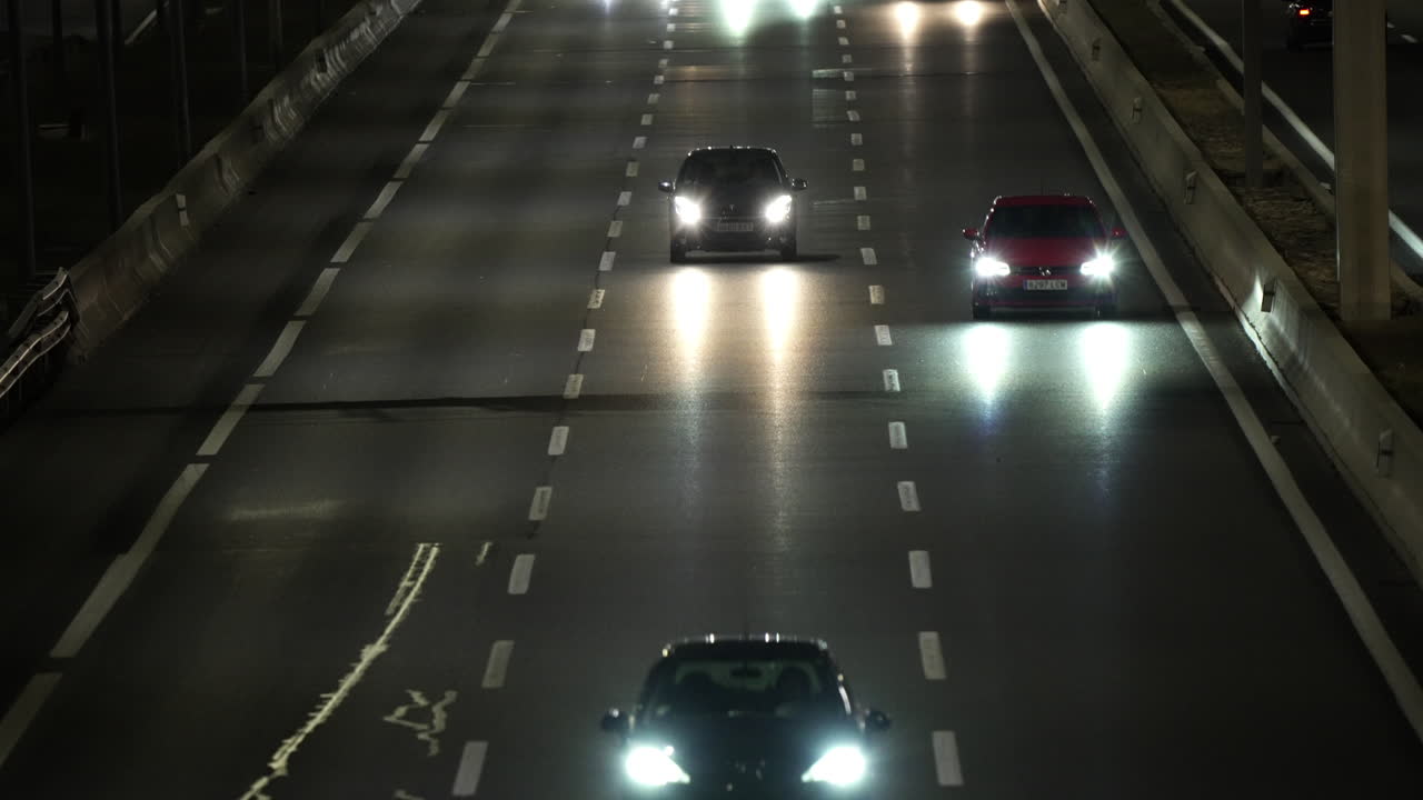 Elevated view of cars driving on a highway at night, their headlights illuminating the road ahead, creating a sense of movement and urban life