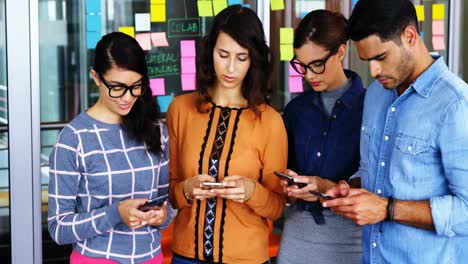 executives standing in a row using mobile phone during meeting