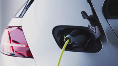 close up of power cable charging environmentally friendly zero emission electric car in garage