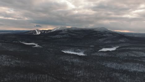 Monochrome-Of-A-Snowy-Forest-And-Mountains-Under-Clouded-Sky-In-Orford,-Quebec,-Canada