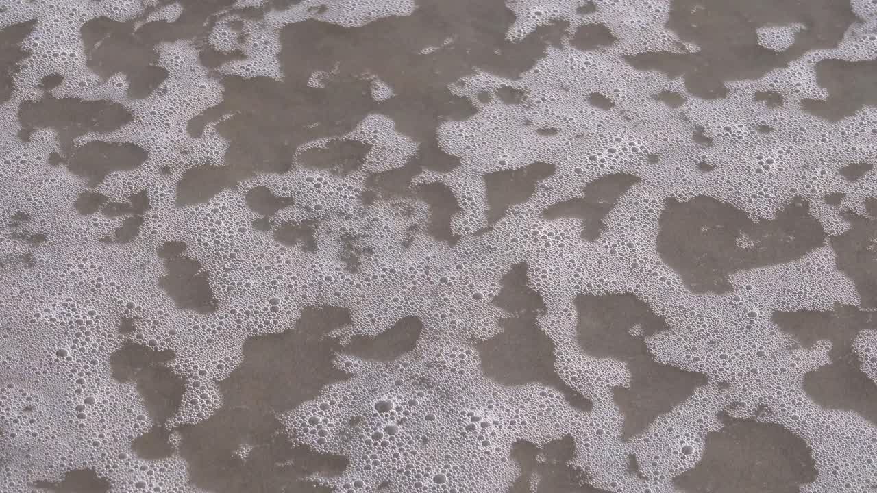 mujer escribe feliz 2021 en la arena en español e inmediatamente una ola lo borra