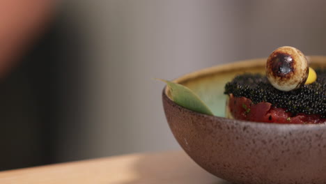 close-up view of tuna tartare with black roe and quail egg on top as garnish