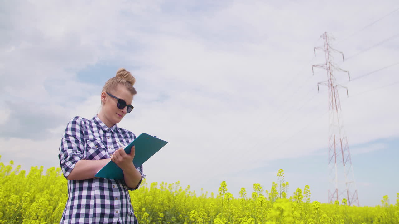 женщина-фермер делает заметки возле поля рапса