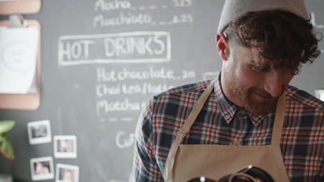 Fröhlicher-Barista-Mann-Bedient-Kunden-Beim-Kaffeekauf-In-Einem-Belebten-Café-Und-Genießt-Den-Freundlichen-Service