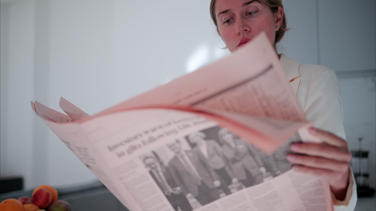 Woman in a white blazer reading the newspaper in the kitchen