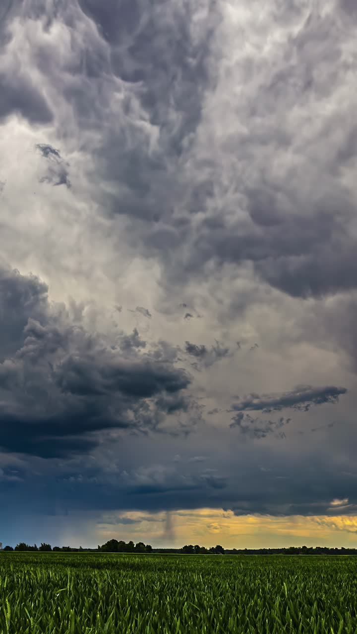 Timelapse of storm clouds drifting across sky above green fields with rain on horizon