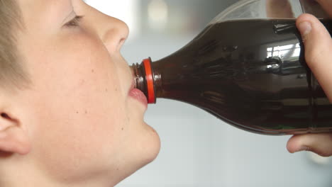 close up of boy drinking soda from bottle