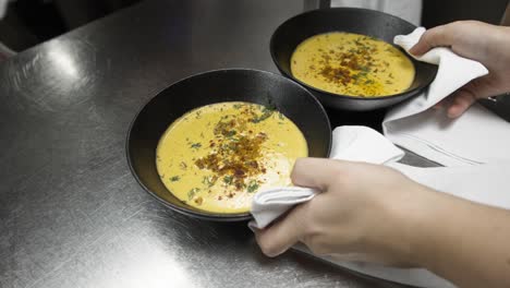 waiter picking up two bowls of soup from kitchen table to serve, slow motion