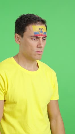 man with ecuadorian flag painted looking away with serious expression