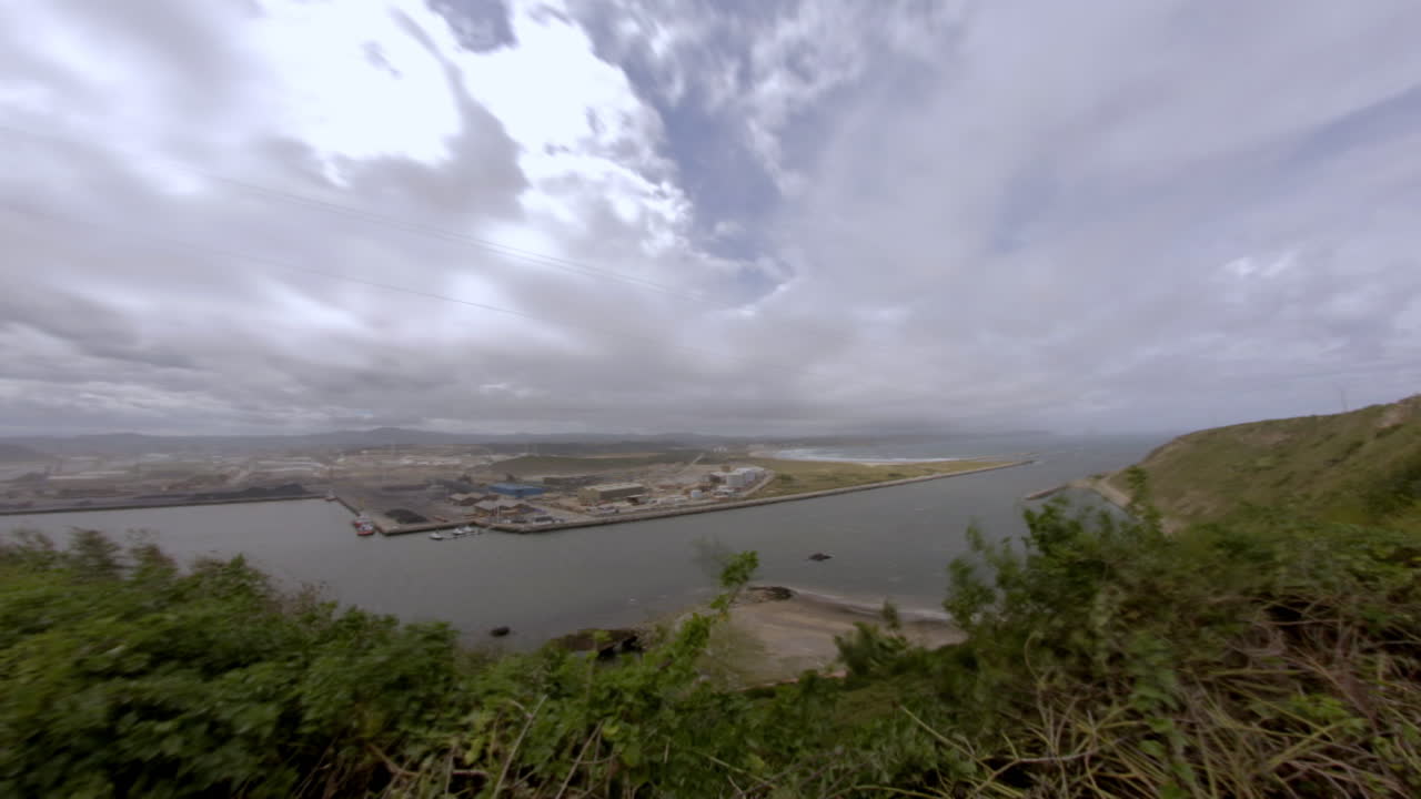 Wide panoramic shot of a coastal port under dramatic cloudy skies