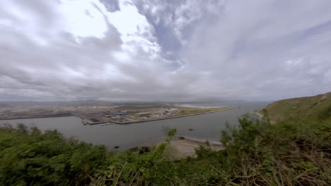 wide panoramic shot of a coastal port under dramatic cloudy skies