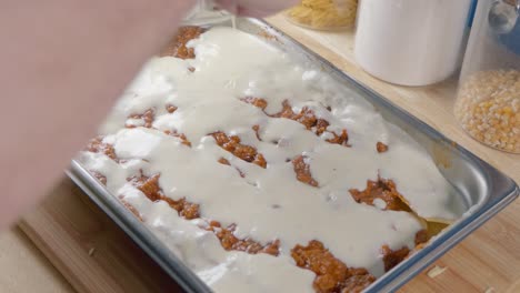 medium shot of adding bechamel sauce to tomato sauce while making lasagne