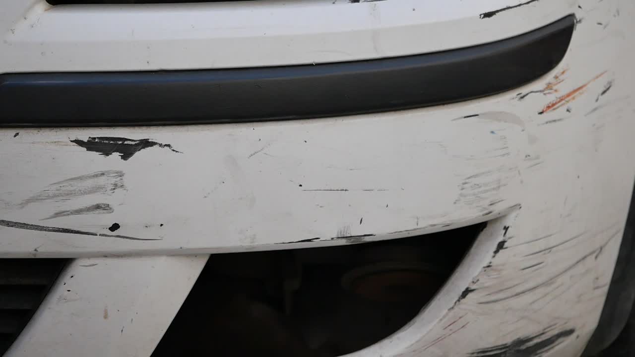 Close-up of a White Car Bumper with Scratches and Damage