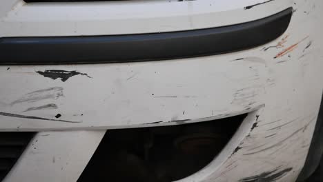close-up of a white car bumper with scratches and damage