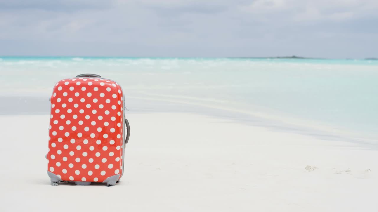 白い砂浜にあるカラフルな旅行用スーツケース。