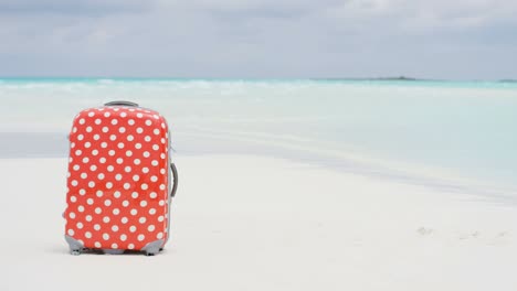 maleta de viaje colorida en una playa de arena blanca