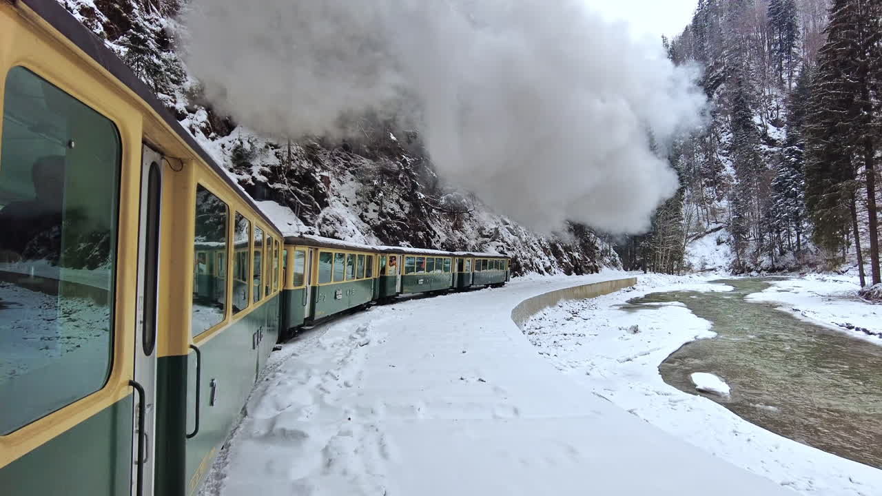 Vista del treno a vapore in movimento Mocanita dall'interno, foresta spoglia e fiume in inverno, neve, riprese dei passeggeri, Romania. Rallentatore