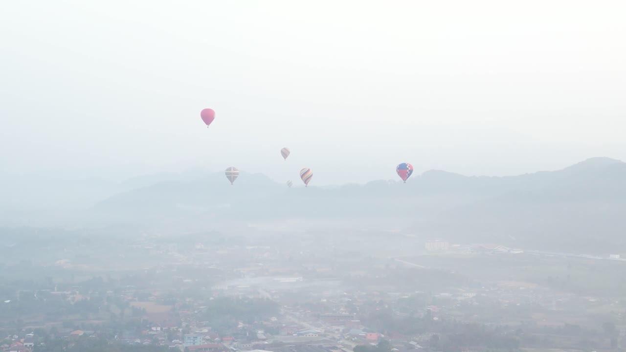 drone shot of hot air balloons rising above the morning mist in Vang Vieng, the adventure capital of Laos
