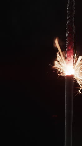Vertical video of lit sparkler and copy space on black background