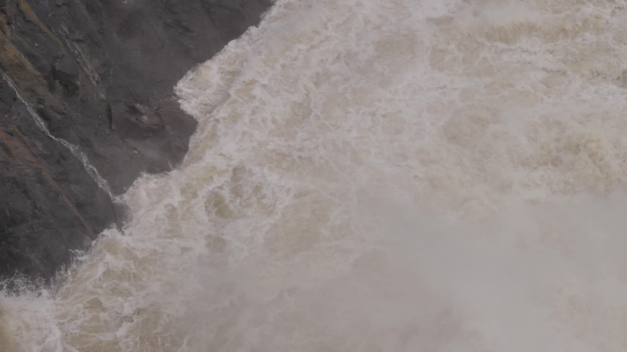 Handheld shot and top view of Hinze Dam water flows under heavy rain during La Ni&ntilde;a, Gold Coast Hinterland, Queensland, Australia