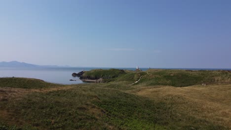 yynys llanddwyn 섬을 가로지르는 공중 뷰 골로디  ⁇ 어 메이어 돌 등대와 안개 스노우도니아 산으로 향하는 산책로