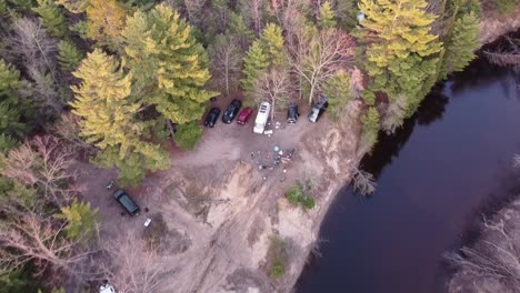 people on overland camping adventure by the river of meskugon with vehicles on remote forest of leota in michigan