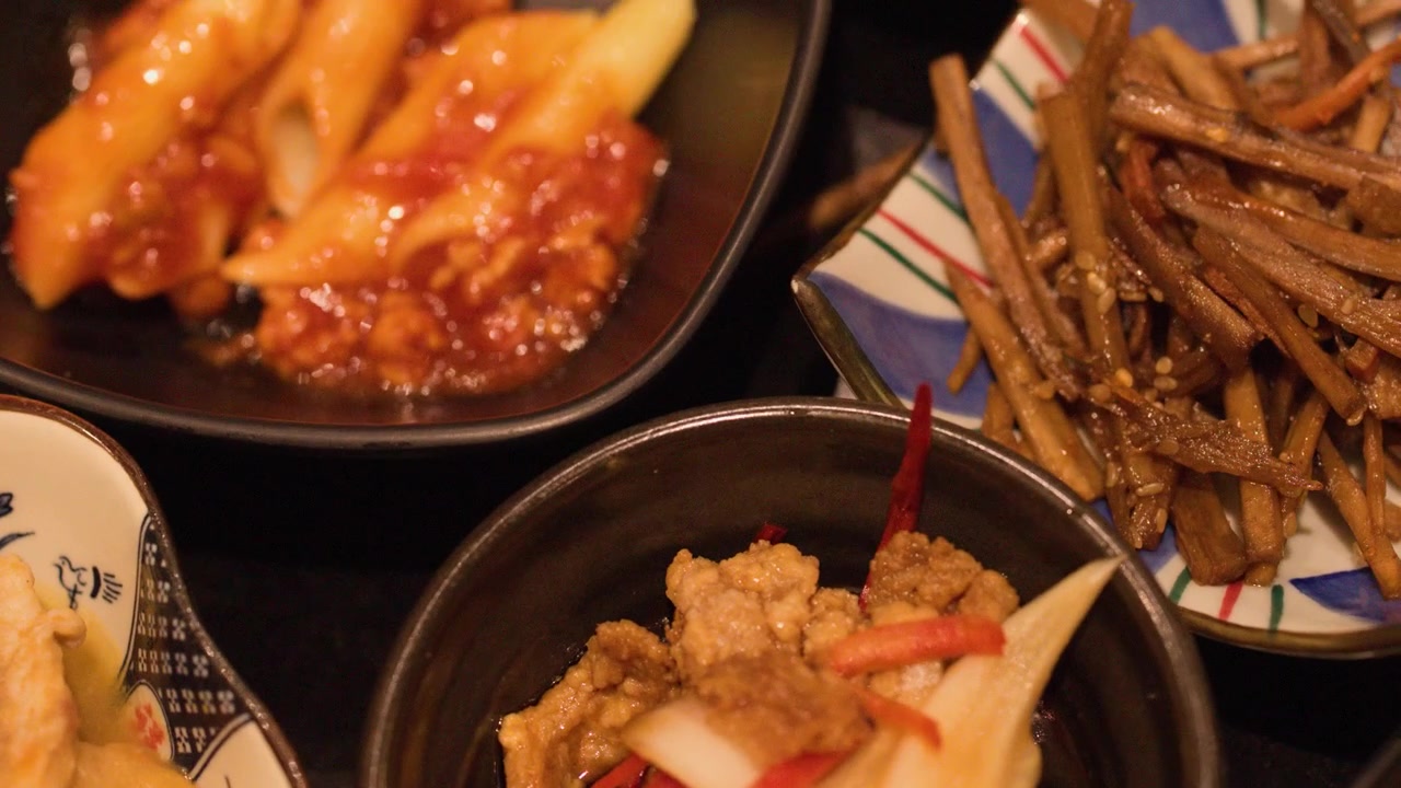 Tampilan dekat berbagai hidangan pembuka Jepang termasuk pasta penne dan sayuran dalam piring keramik
